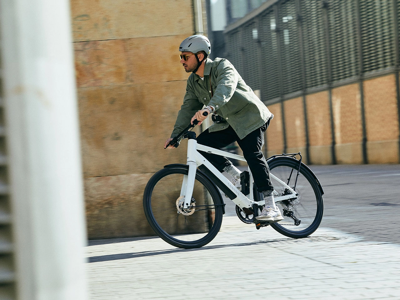 Radfährer fährt mit einem weißen Canyon um eine Straßenecke
